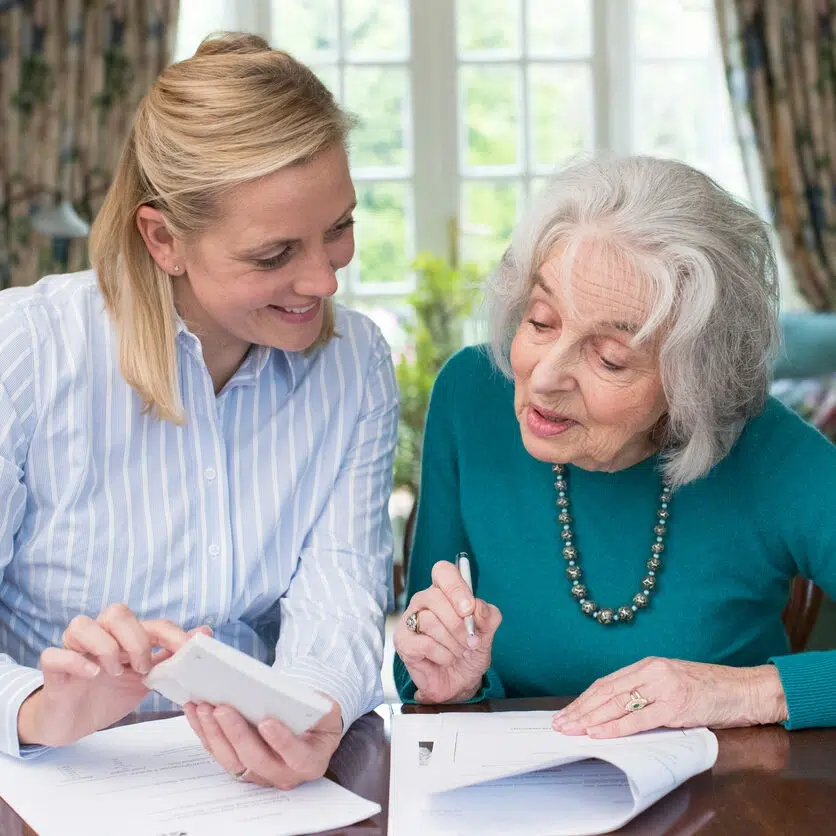Woman Helping Senior Neighbor With Paperwork